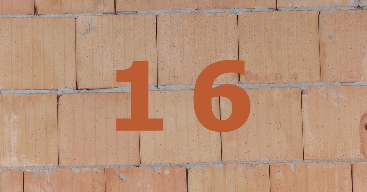 Orange Zahl 16 auf gemauerter Häuserwand.