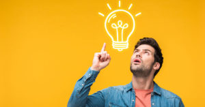 Einem Immobiliensuchenden mit erhobenem rechten Zeigefinger vor einem gelben Hintergrund geht ein Licht auf, dargestellt als Grafik einer Glühbirne zwischen seinem Kopf und dem erhobenen Zeigefinger | Immobilie suchen und finden
