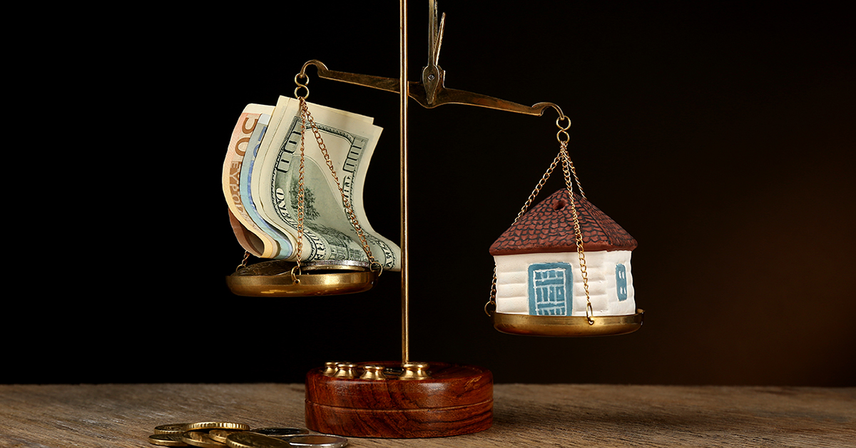 Scale with money and model of house on dark background; Wertermittlung